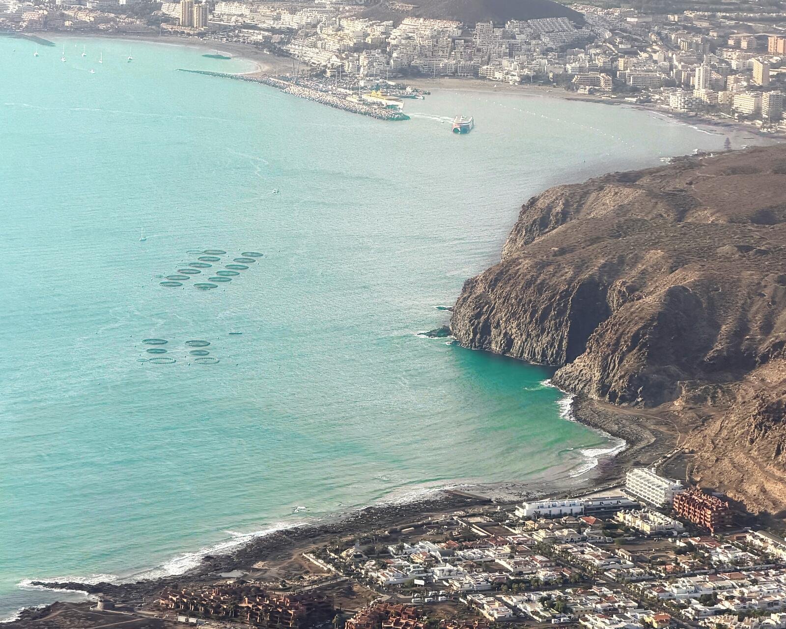 Vista aerea della costa di Palm-Mar con il percorso in kayak nei suoi sei tratti: spiaggia La Arenita, allevamenti ittici, Baia delle Tartarughe, il Bufadero, zona snorkeling e Grotta degli Innamorati. Sullo sfondo, Los Cristianos.
