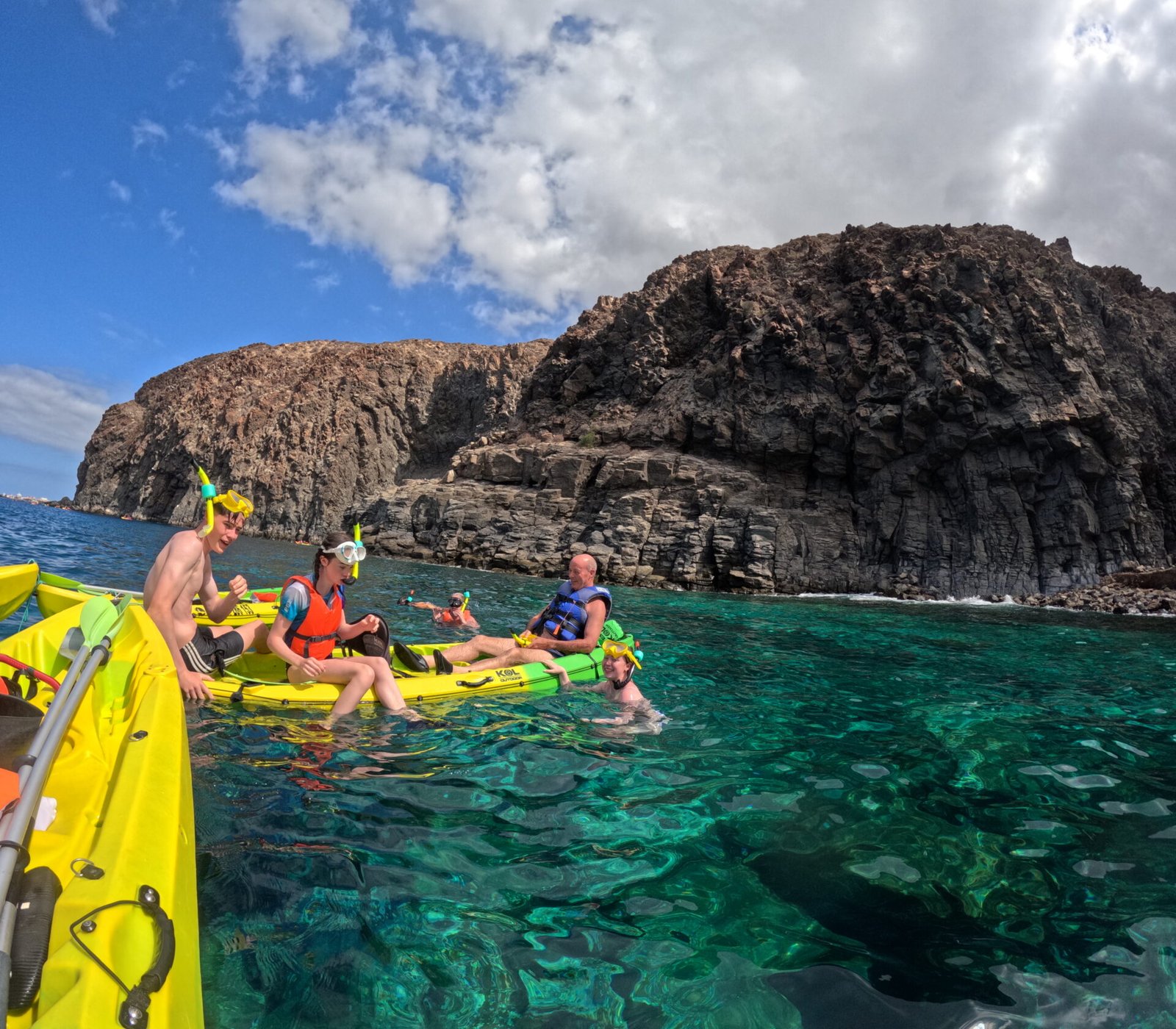 Group in kayaks by the volcanic rock of Mal País, on clear green water