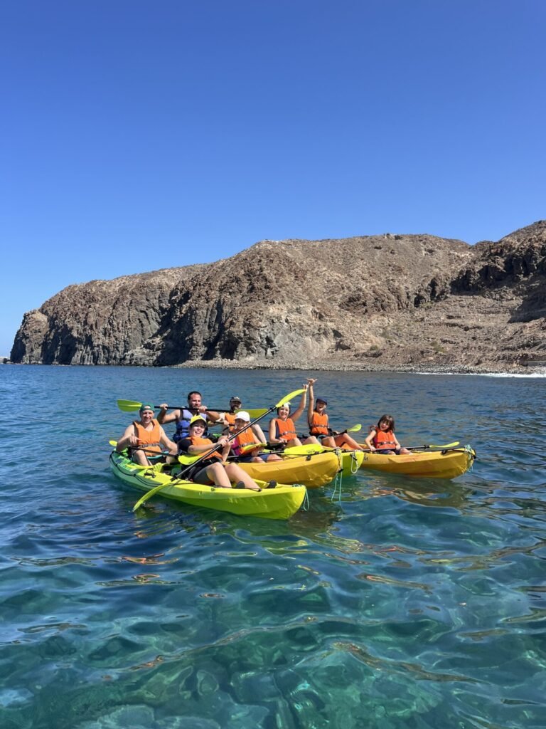 Grupo en kayaks sobre agua cristalina frente a la costa de Palm-Mar