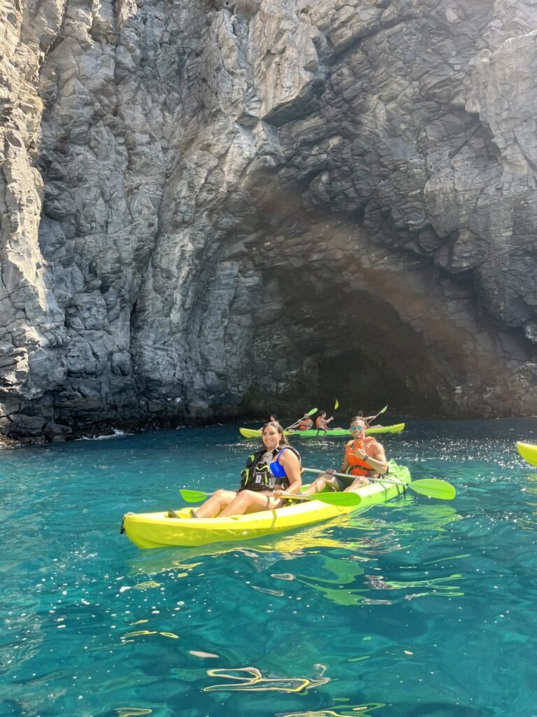 Two yellow kayaks beside a volcanic rock cave, on turquoise water